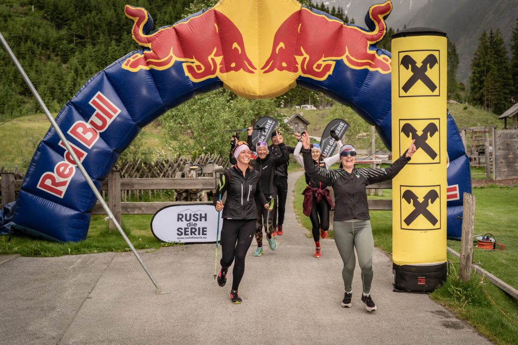 Jubelnde Sportler beim VenedigerRUSH Bergtriathlon im Salzburger Land unter Red Bull Bogen
